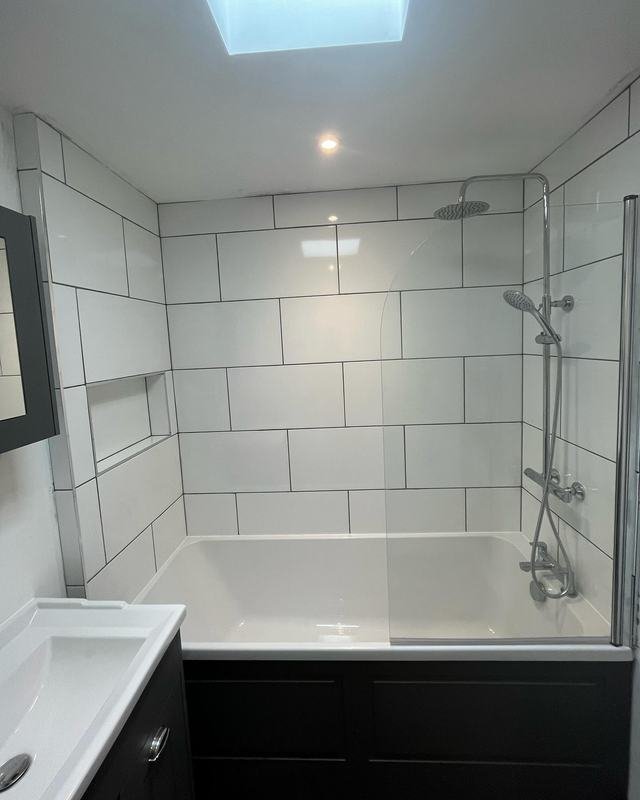 Bathroom with white metro tiles, a skylight and a rainfall shower over the bath