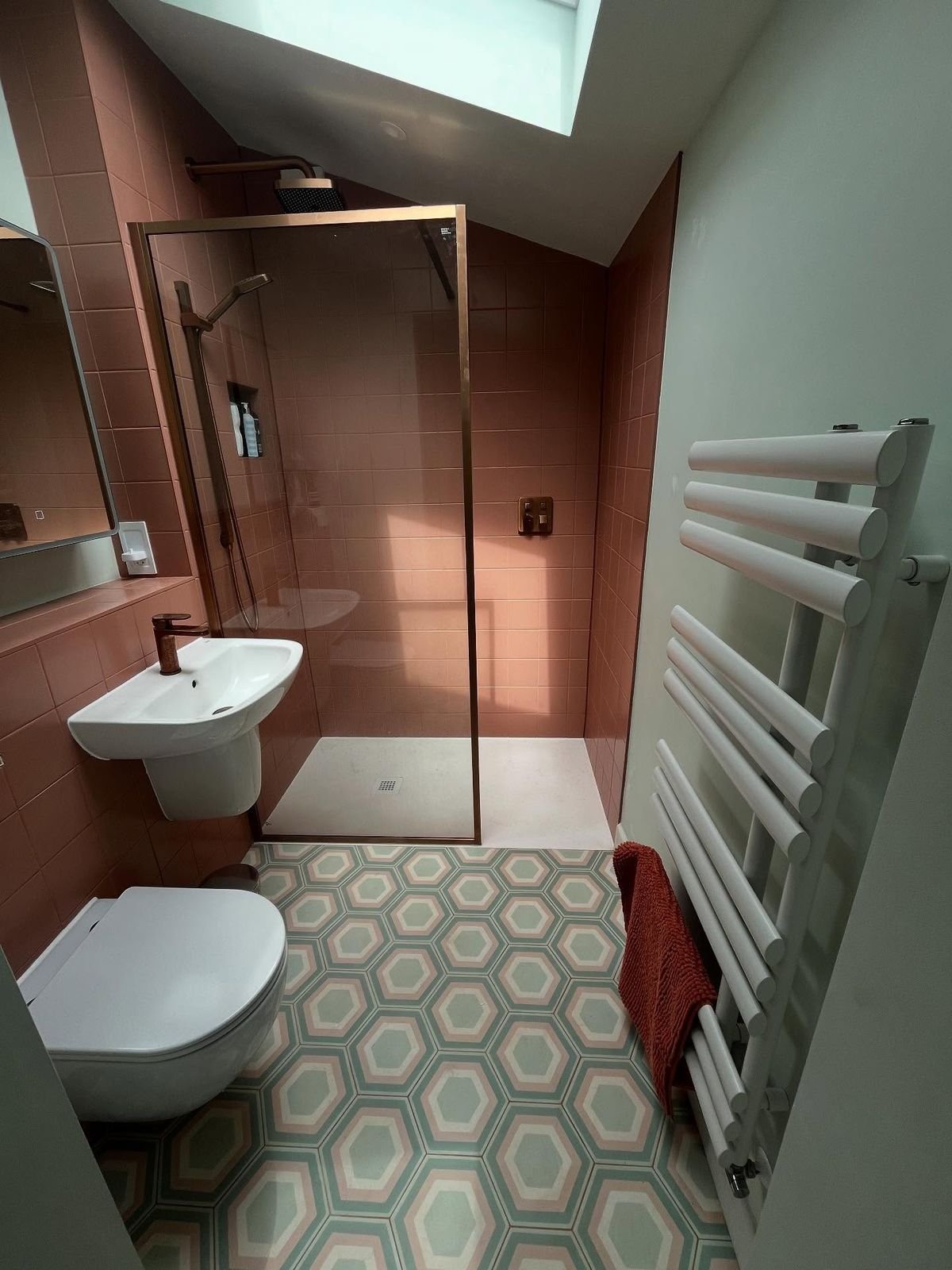 Bathroom with terracotta tiles, a sage green wall, hexagonal floor tiles and a white towel radiator