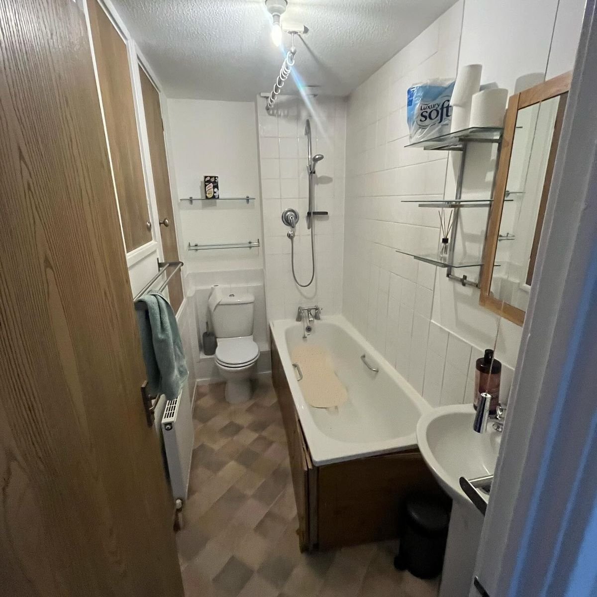 Didcot bathroom before: white wall tiles, a bath and a pedestal basin