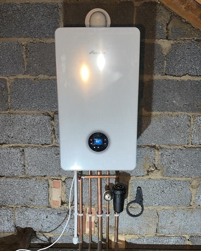 White combination boiler fixed to a block wall with new copper pipework