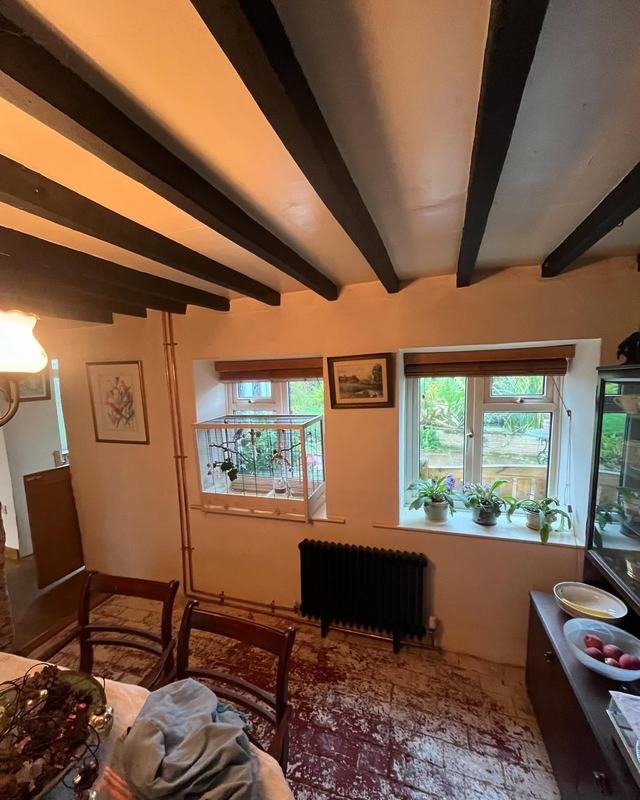Cast iron style radiator beneath a beamed ceiling in an old cottage