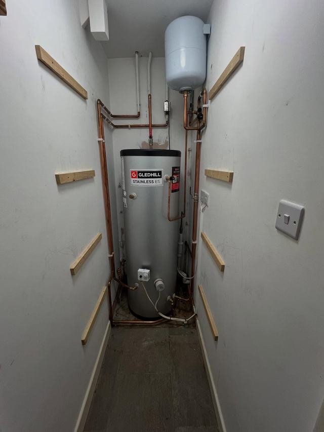 Unvented cylinder in a narrow cupboard with copper pipework on both walls