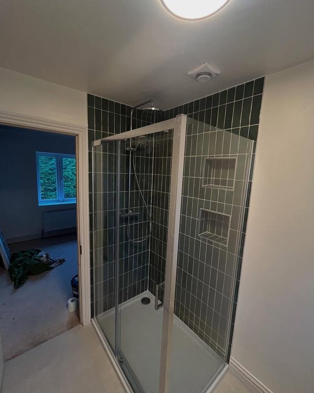 Shower enclosure with green metro tiles and recessed shelves